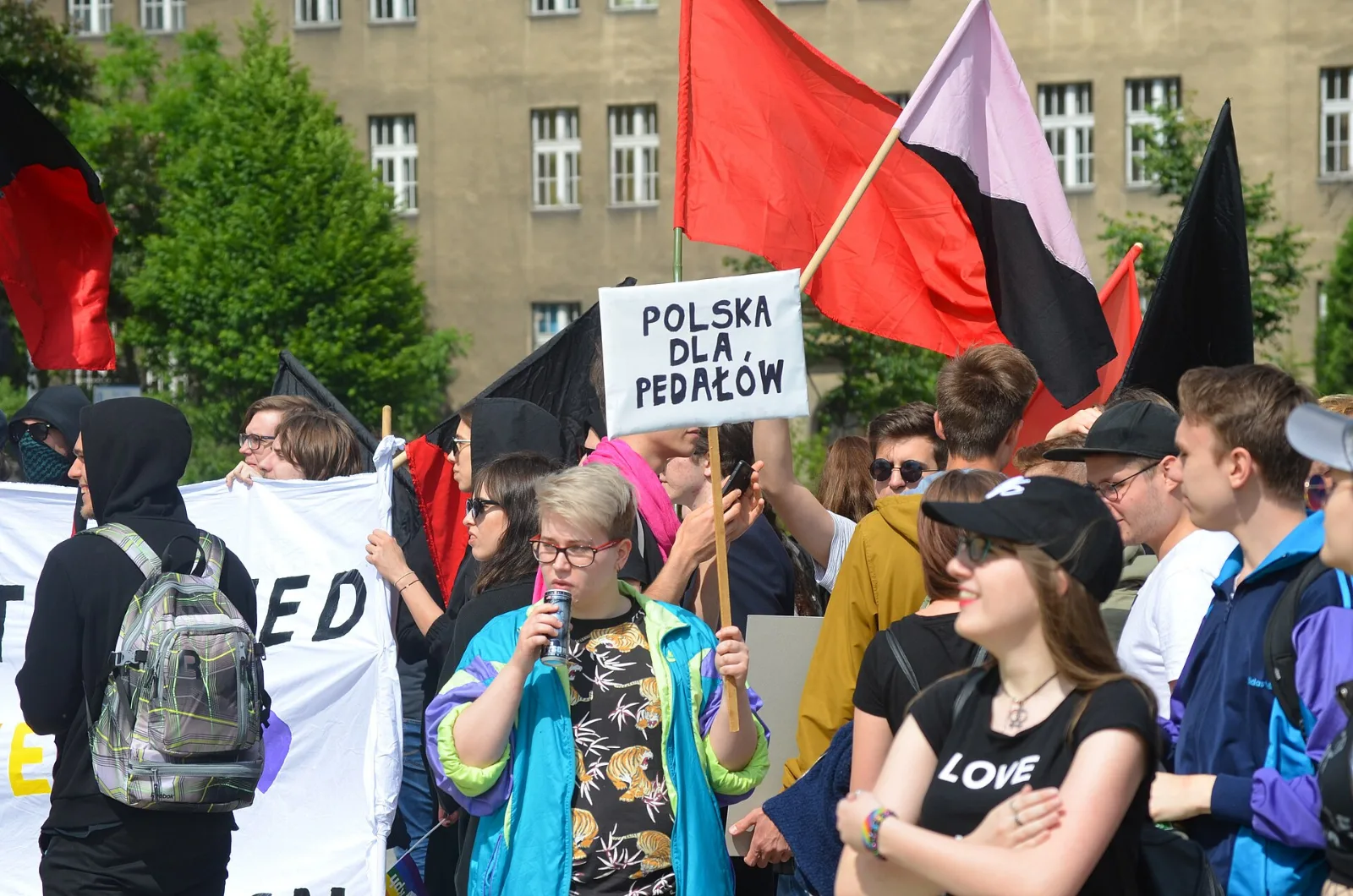 Marchers at the Kraków equality march carrying a pink and black diagonal flag.
