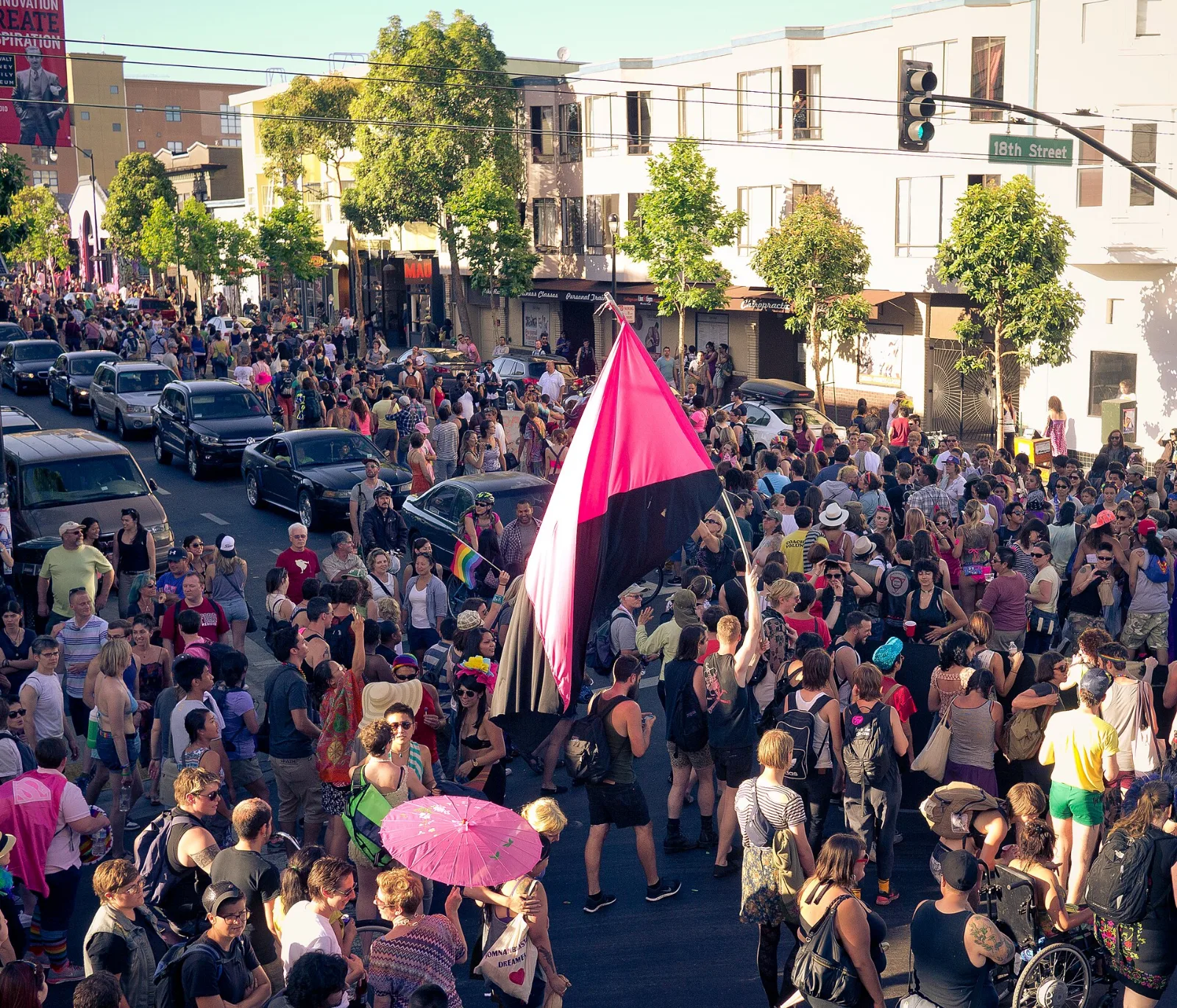 Marchers at the San Francisco Dyke March carrying a flag divided diagonally, pink above black.