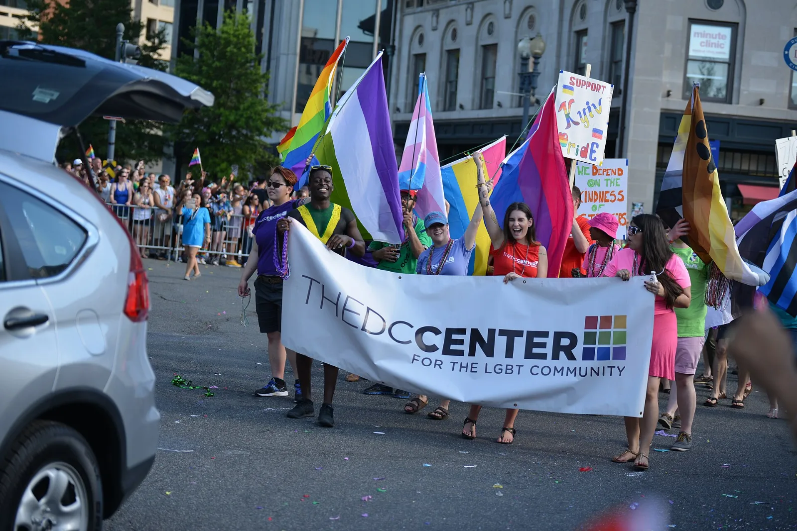 Marchers carrying several Pride flags, among them a pink, purple and blue Bisexual flag.