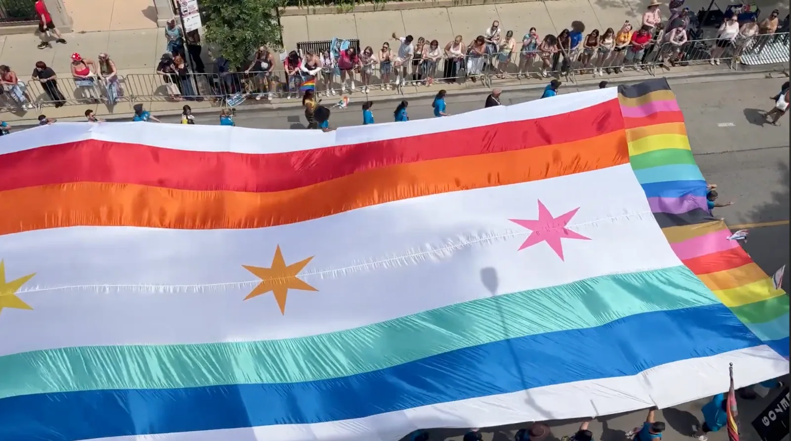 Aerial view of the Chicago flag in rainbow pride colors carried through the Chicago Pride Parade, 2026