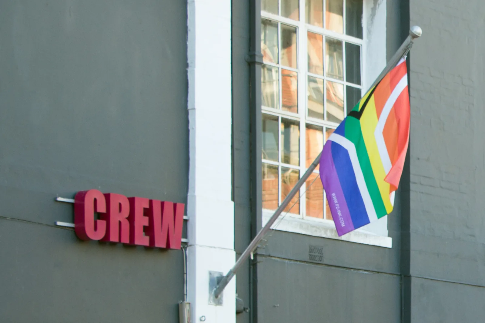 The flag on a bracket above a street doorway in a row of painted buildings.