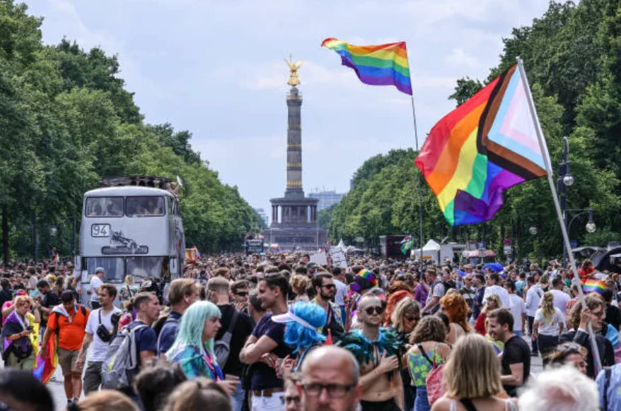 Progress Pride Flag waving above the crowd at Christopher Street Day with the Victory Column in the background, Berlin, July 22, 2023