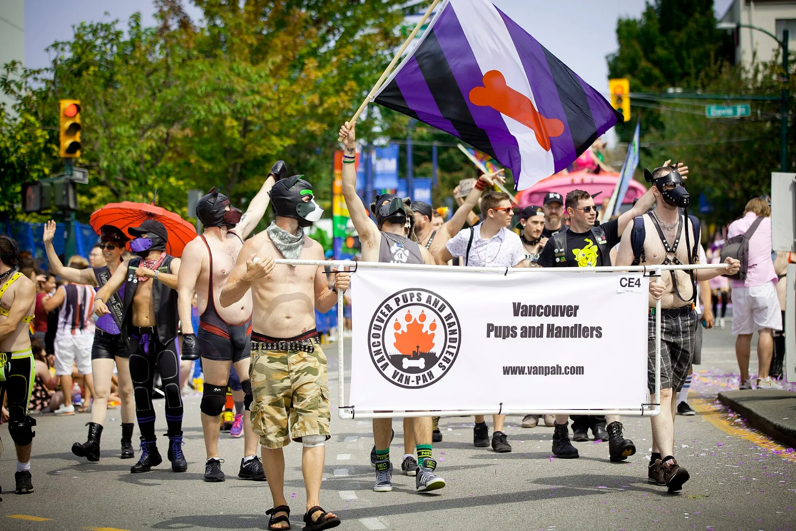 A Puppy Pride Flag at the Vancouver Pride parade, marchers in pup hoods beside it.