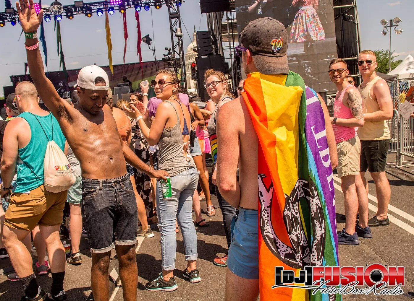 A festivalgoer at the 2017 Capital Pride festival in Washington, DC, wearing a rainbow Gadsden flag as a cape, with the United States Capitol dome in the background.