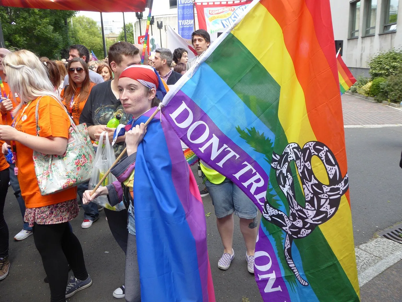 A marcher at Newcastle Pride 2015 carrying a large rainbow Gadsden flag with a coiled snake and the words DONT TREAD ON ME.