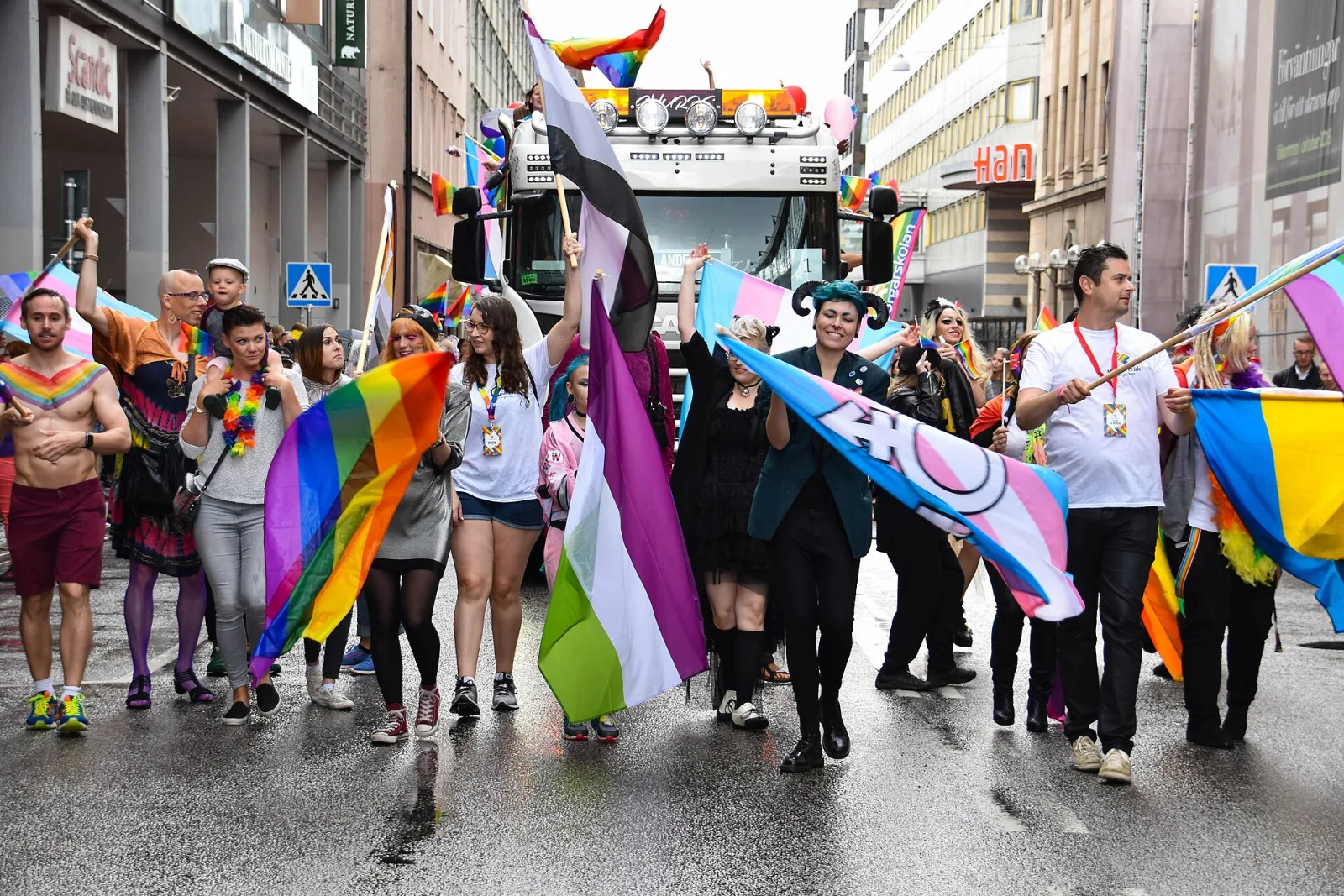 Marchers carrying several pride flags, one of them a transgender flag charged with the transgender symbol.