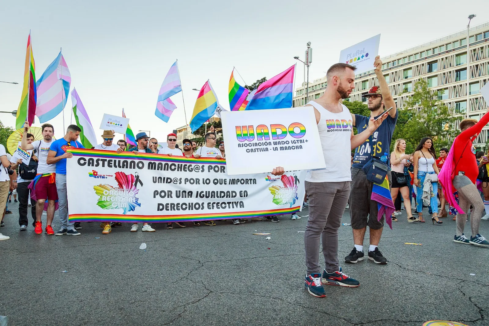Marchers carrying several Pride flags, among them a pink, purple and blue Bisexual flag.