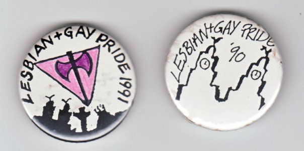 Two worn pin badges on a white ground. The left badge, lettered LESBIAN + GAY PRIDE 1991 around its rim, carries a pink inverted triangle with a black double-headed axe drawn across it, above black silhouettes of marchers with raised fists. The right badge, lettered LESBIAN+GAY PRIDE '90, carries a drawn city skyline of towers and figures.