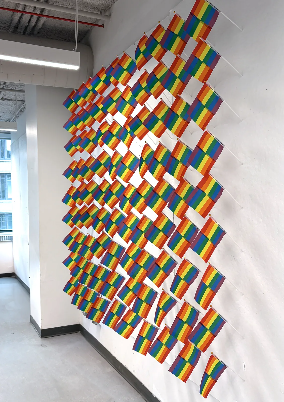 Right to Assemble — the mini Pride flags installation seen along the wall